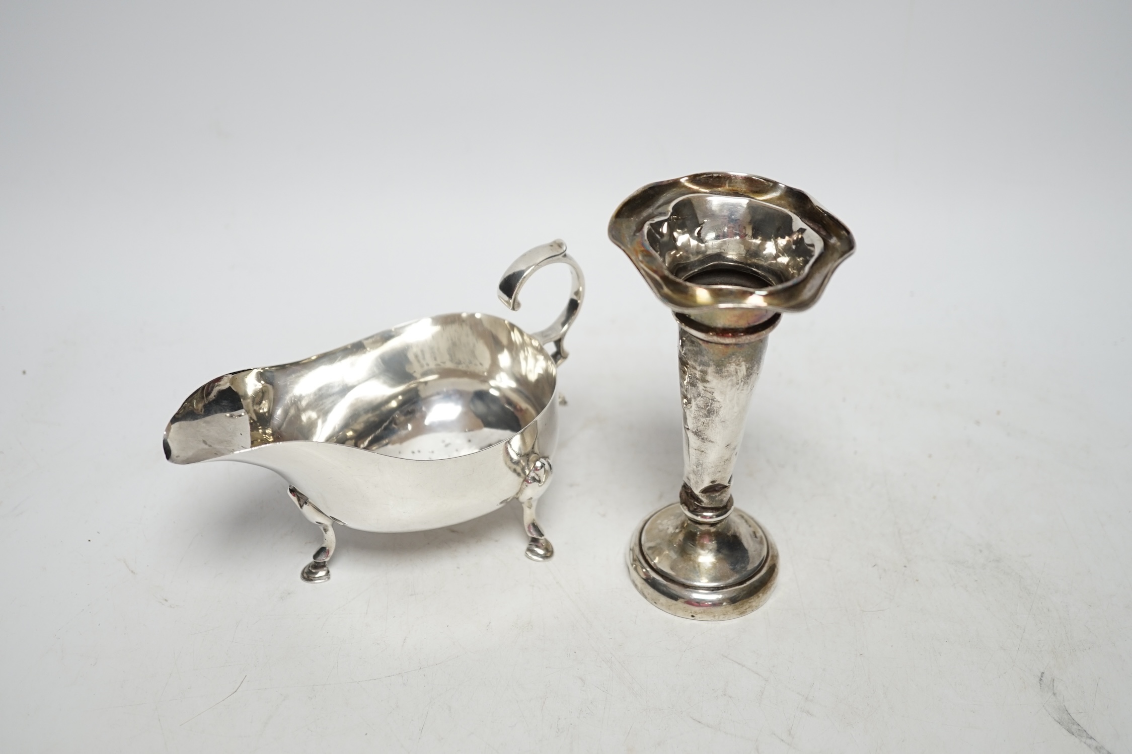 A George V silver sauceboat, Sheffield 1925, 14.5cm, 4.2oz and a similar silver mounted posy vase. Fair and poor condition.
